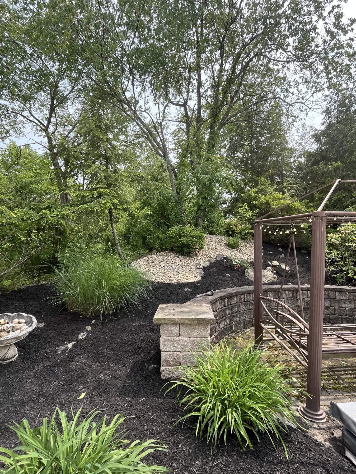 Pergola, ornamental grasses, and stone wall garden vignette