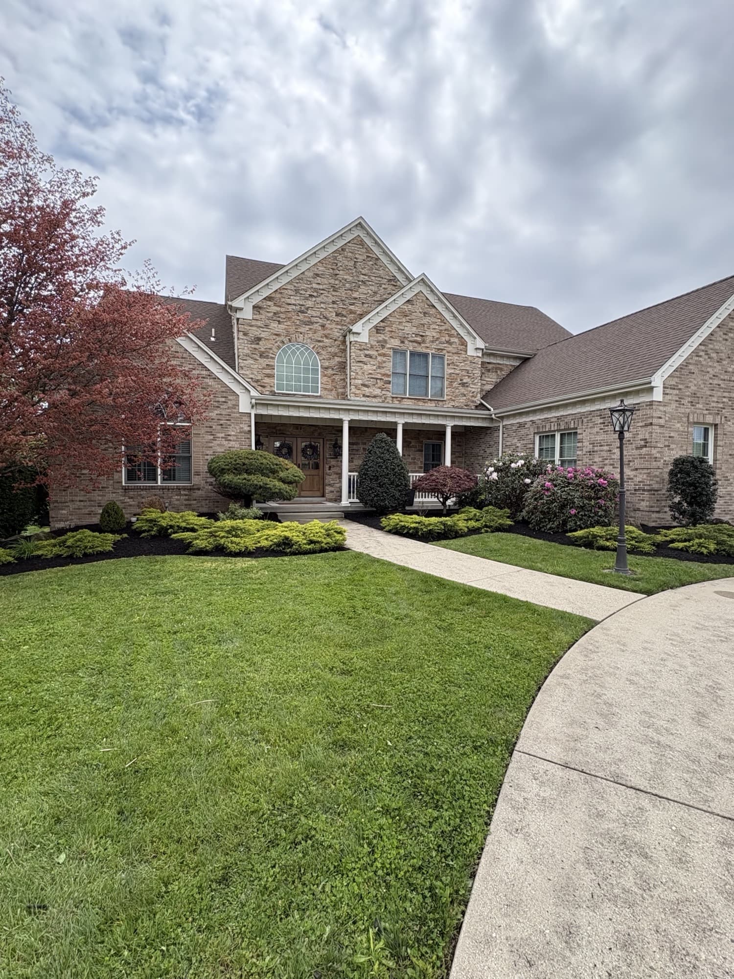 Brick home with manicured front lawn and shaped shrubs